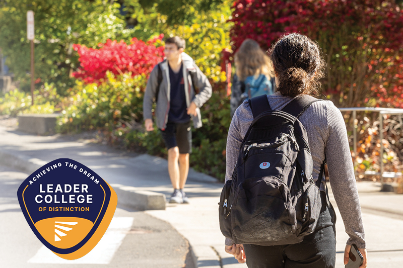 Three students walking with Bellevue College campus in the background